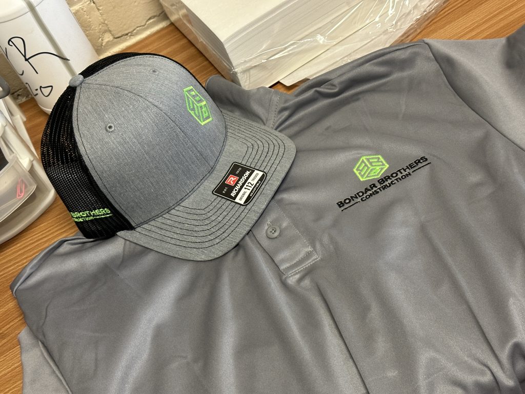 Custom embroidery on the left panel of a baseball cap and left chest of a polo shirt. Matching logo embroidery for a local construction company