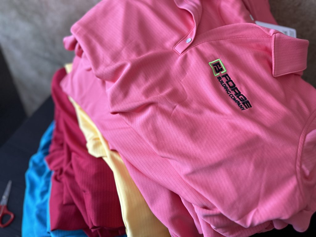 An assortment of bulk embroidered polos with a 2-color left chest logo placement for a local business in Boise, Idaho.