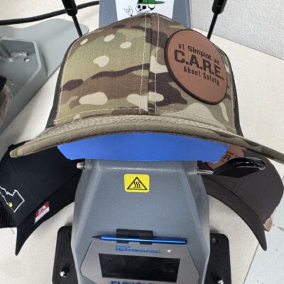 Pressing leather patch onto a camo hat at The Print Plug in Nampa